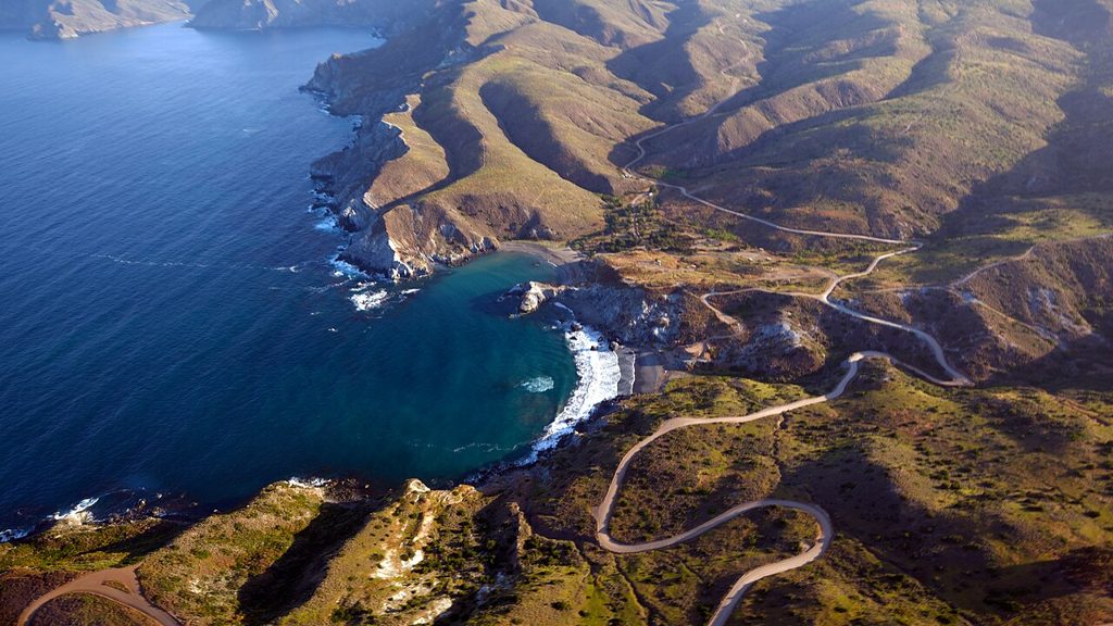 A remote Catalina Island cove seen from the air, deep blue water against steep brown hills
