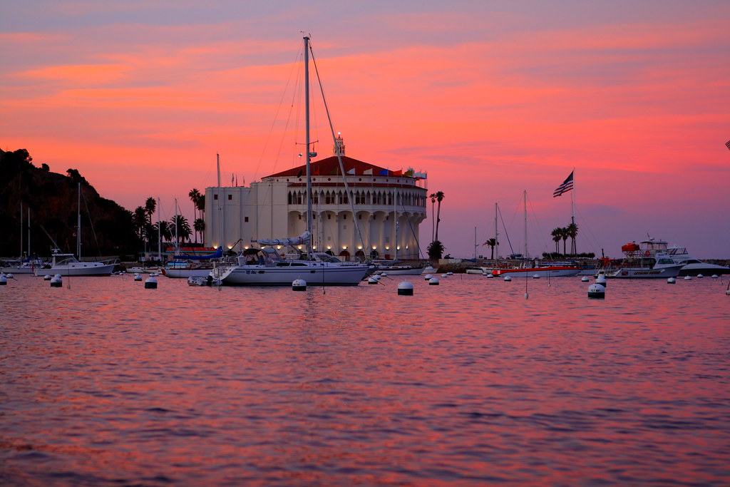 The Avalon Casino and moored sailboats under a pink and orange sunset
